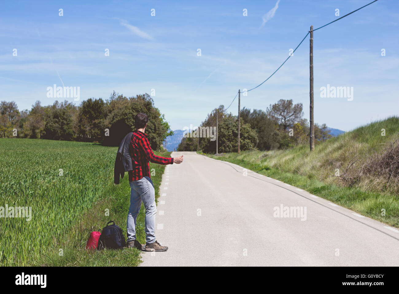 Hipster facendo autostop in strada Foto Stock