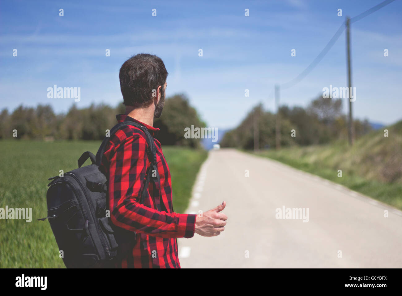 Hipster facendo autostop in strada Foto Stock