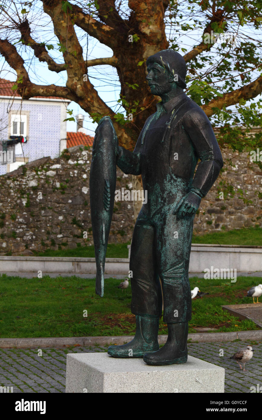 Statua di bronzo di pescatore azienda pesci, parte delle vecchie mura della città in background Caminha, Provincia del Minho, Portogallo settentrionale Foto Stock