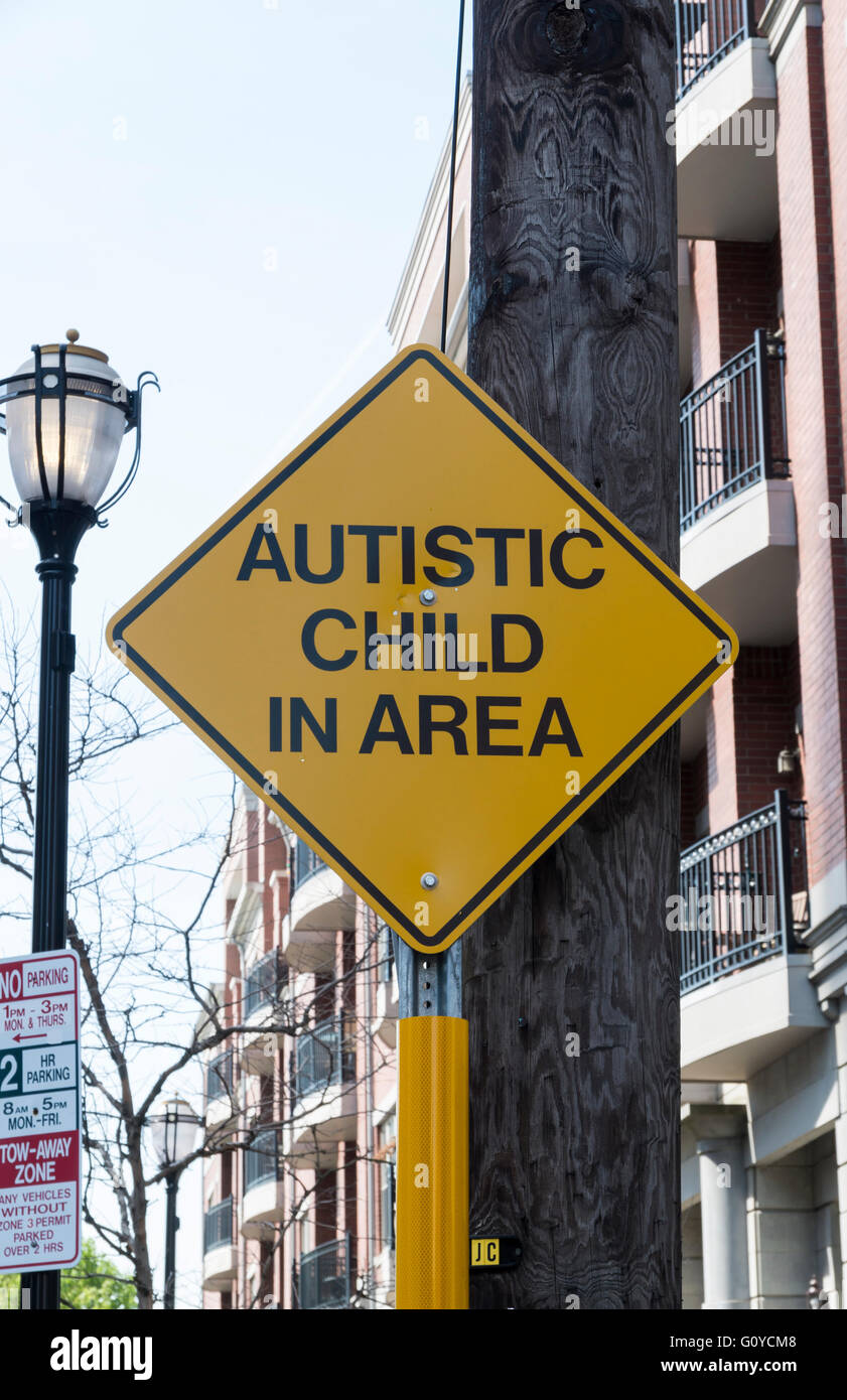 Cartello giallo in una città statunitense strada residenziale driver cautioning circa un bambino autistico nella zona Foto Stock