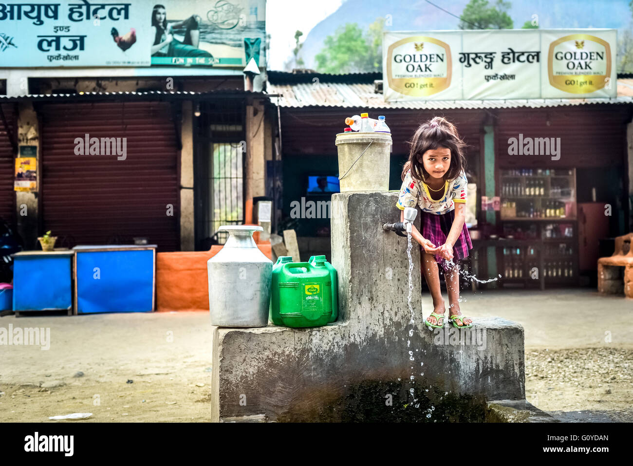 Una bambina che usa l'acqua da un punto di uscita alla periferia della città di montagna di Dhulikhel, Nepal. Foto Stock