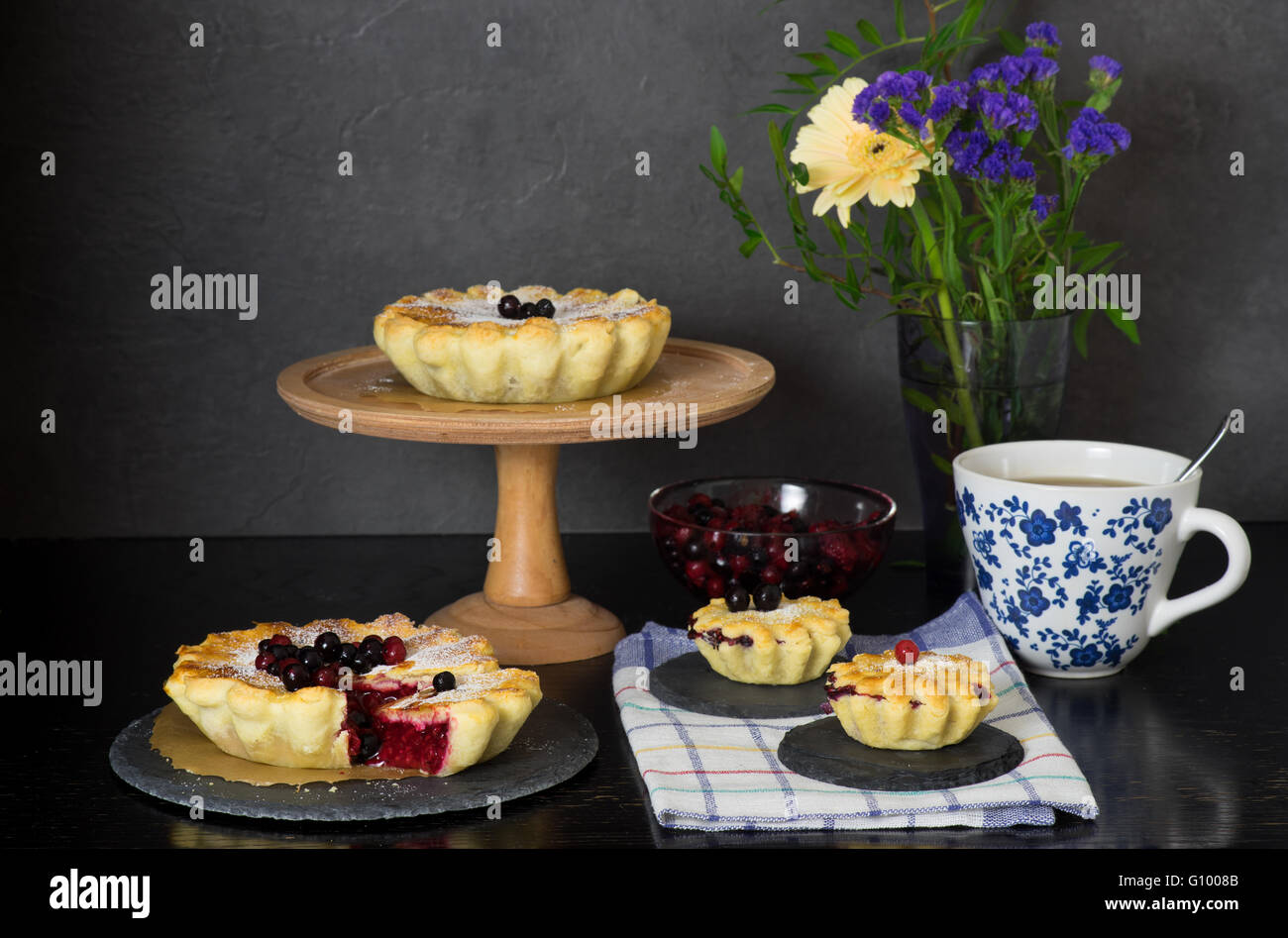 Ancora in vita con bacche di torte e la tazza di tè in stile rustico in legno scuro dello sfondo Foto Stock