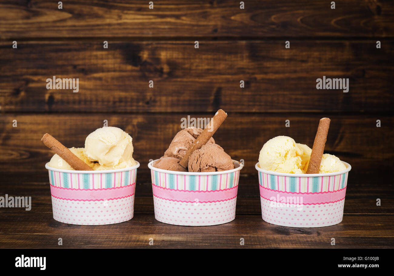 A tre differenti tipi di gelato fatto in casa in bicchieri di carta su legno scuro dello sfondo Foto Stock