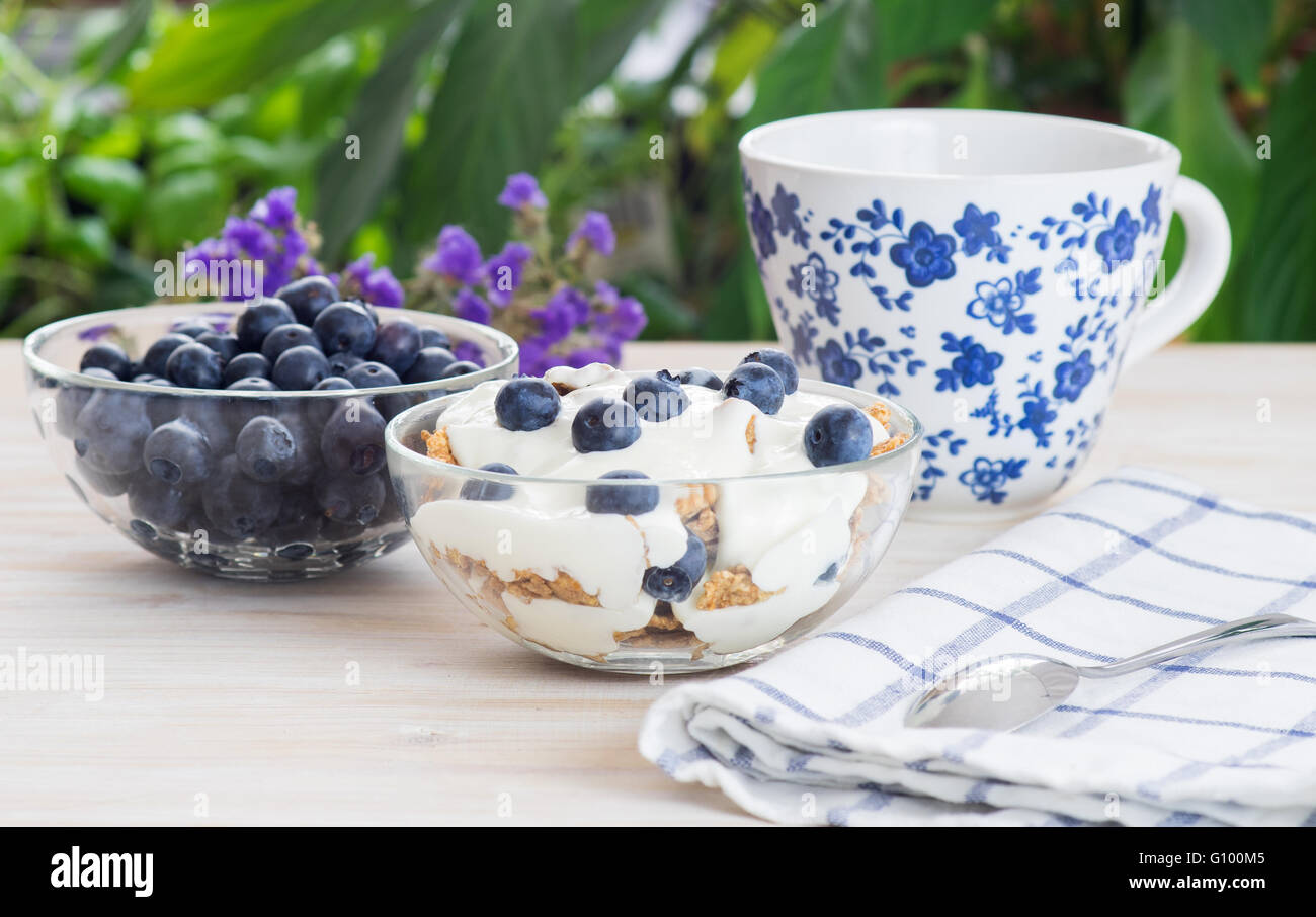 Grano Fitness muesli con yogurt, blackberry e tè sul tavolo di legno su sfondo verde Foto Stock