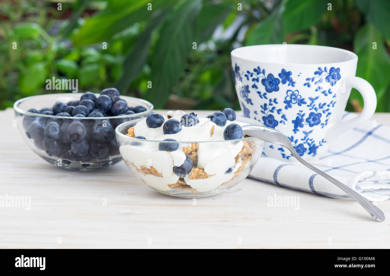 Grano Fitness muesli con yogurt, blackberry e tè bianco sul tavolo di legno Foto Stock