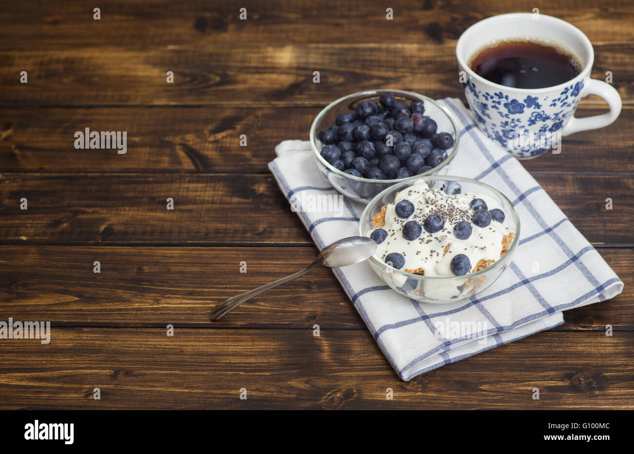 Grano Fitness muesli con yogurt, blackberry e tè scuro sul tavolo di legno Foto Stock
