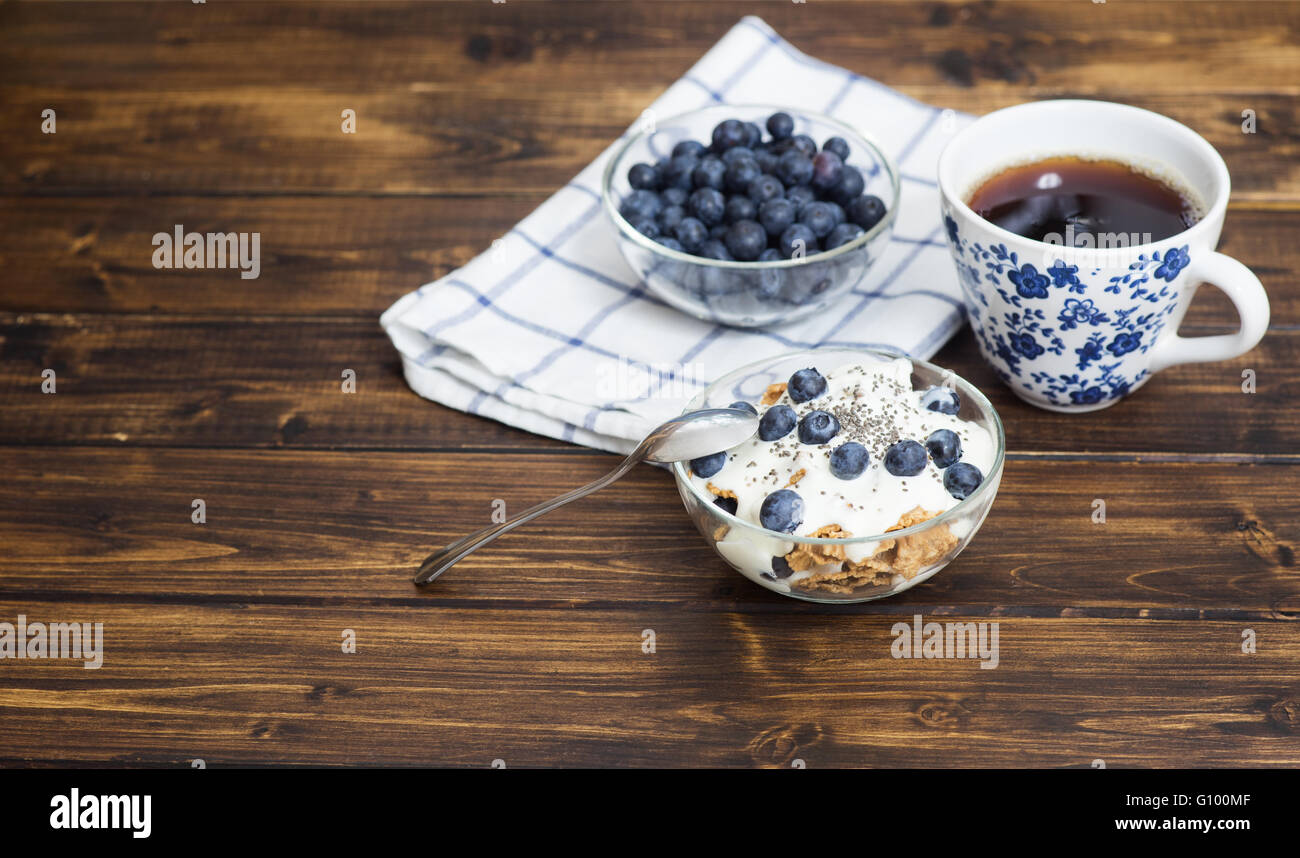 Grano Fitness muesli con yogurt, blackberry e tè scuro sul tavolo di legno Foto Stock