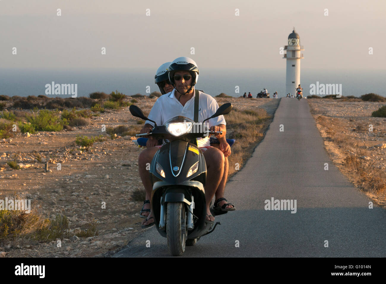 Due giovani motociclisti su una lunga strada di Es Cap de Barbaria faro, a Formentera, isole Baleari. Spagna. Barbaria cape formentera lighthouse road. Foto Stock