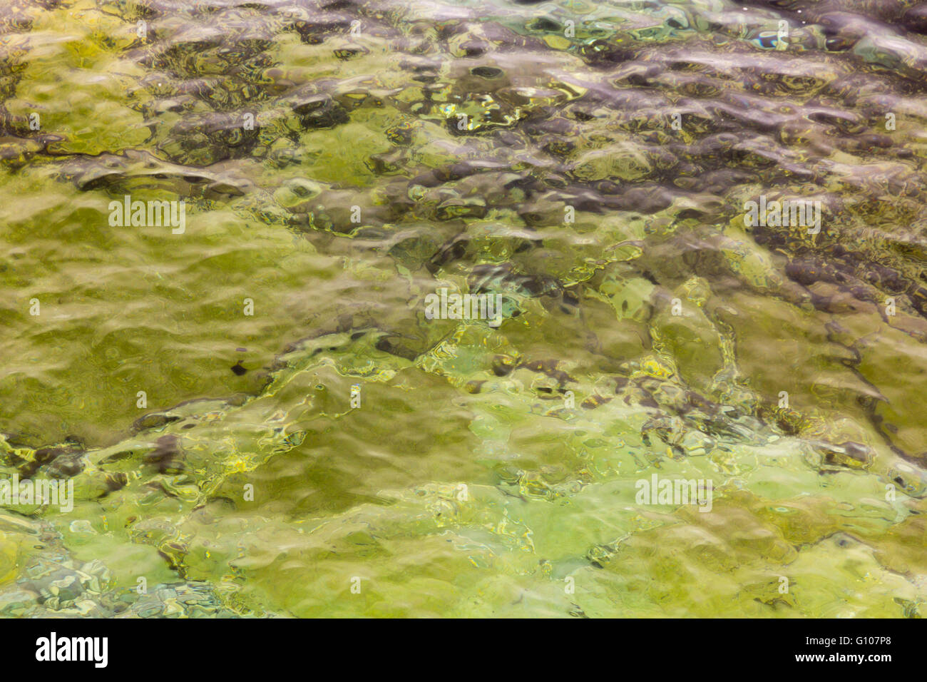 Sfondo con acqua cristallina e piccole onde e rocce Foto Stock