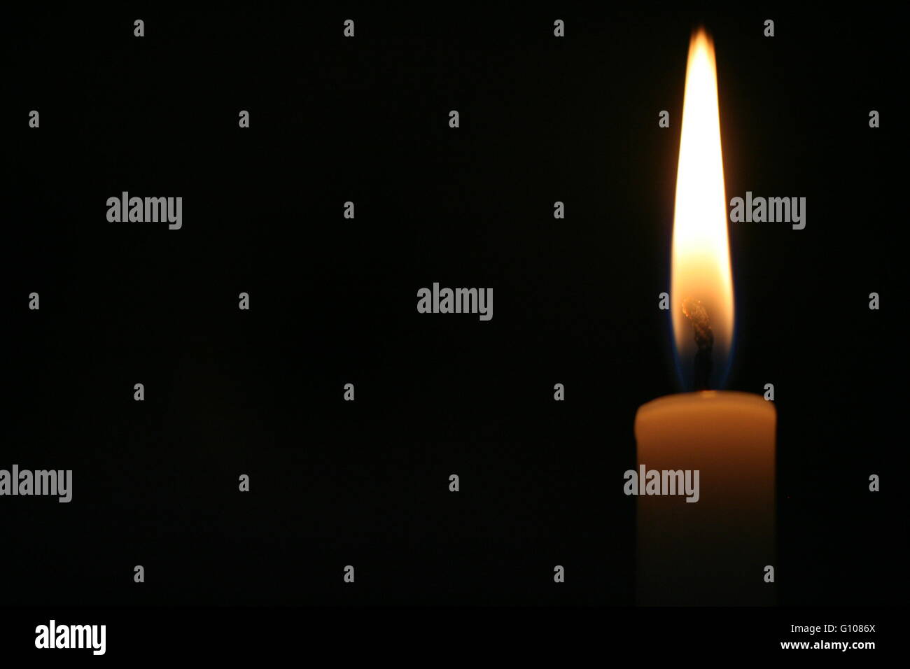 Candela contro uno sfondo nero in una chiesa Foto Stock