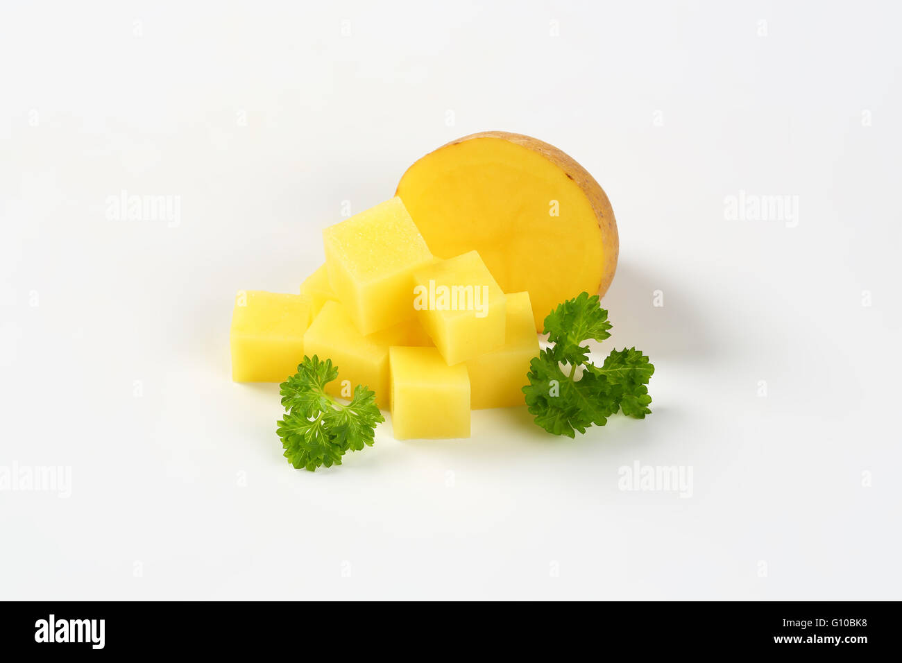 Dimezzati e crudo tagliato a dadini di patate con prezzemolo su sfondo bianco Foto Stock