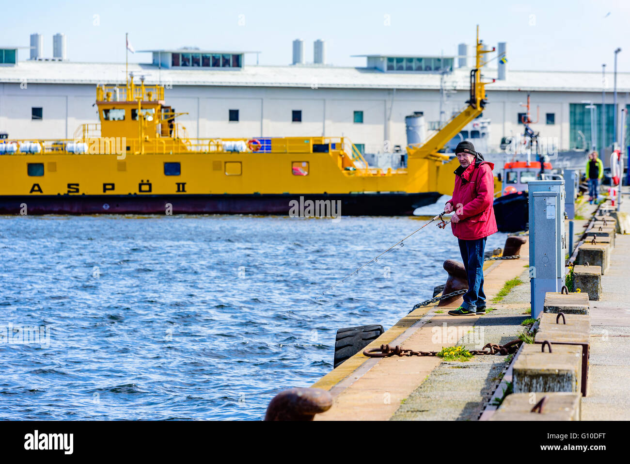 Karlskrona, Svezia - 03 Maggio 2016: maschio anziano pescatore dockside permanente nella parte anteriore di un traghetto per auto la pesca di aringhe. Persone reali Foto Stock