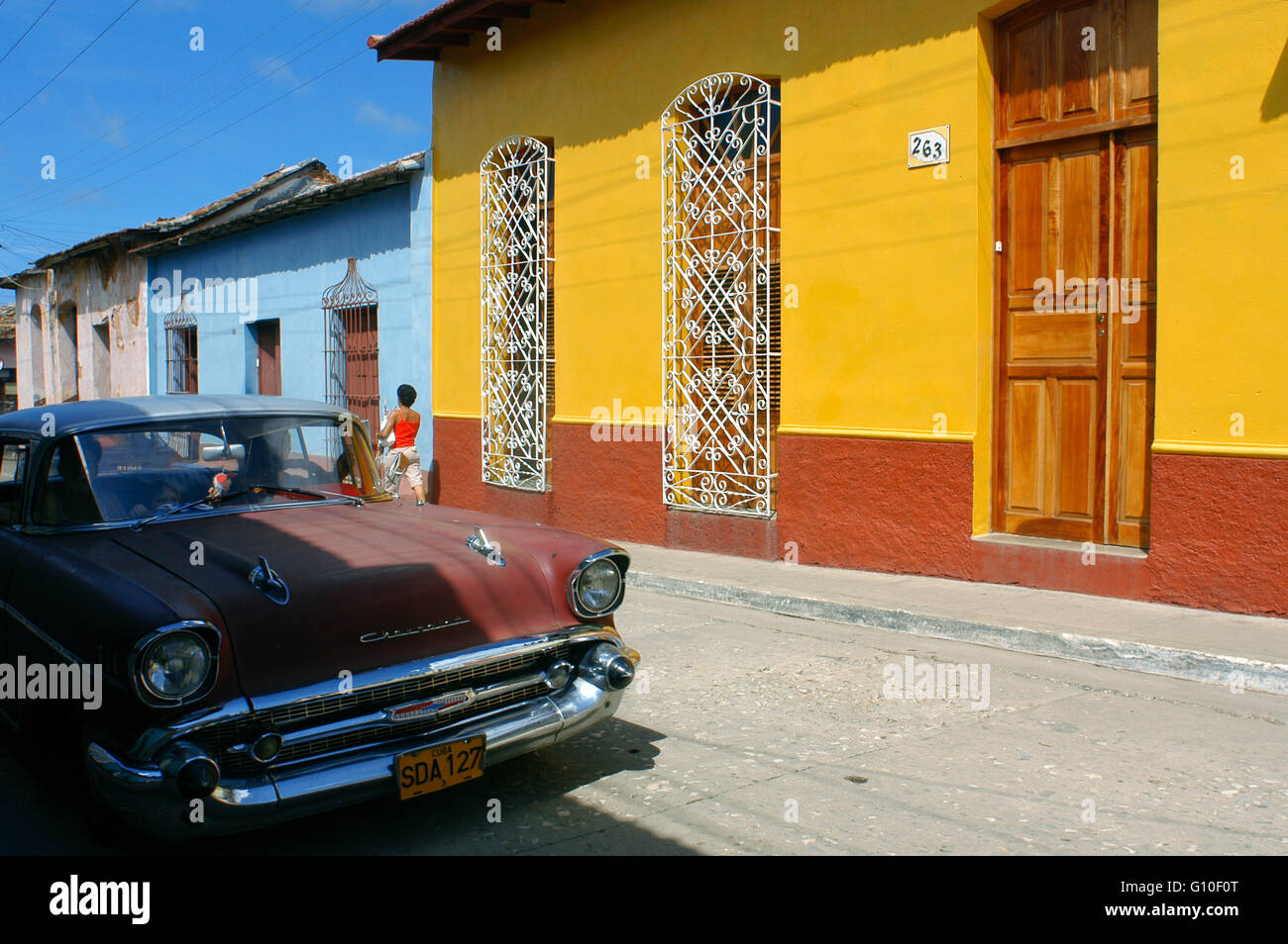 Case colorate in una scena di strada. Vecchio rosso Chevrolet Classic American automobile parcheggiata su una strada con i tradizionali, in background, Trinidad, Cuba, West Indies, America Centrale Foto Stock