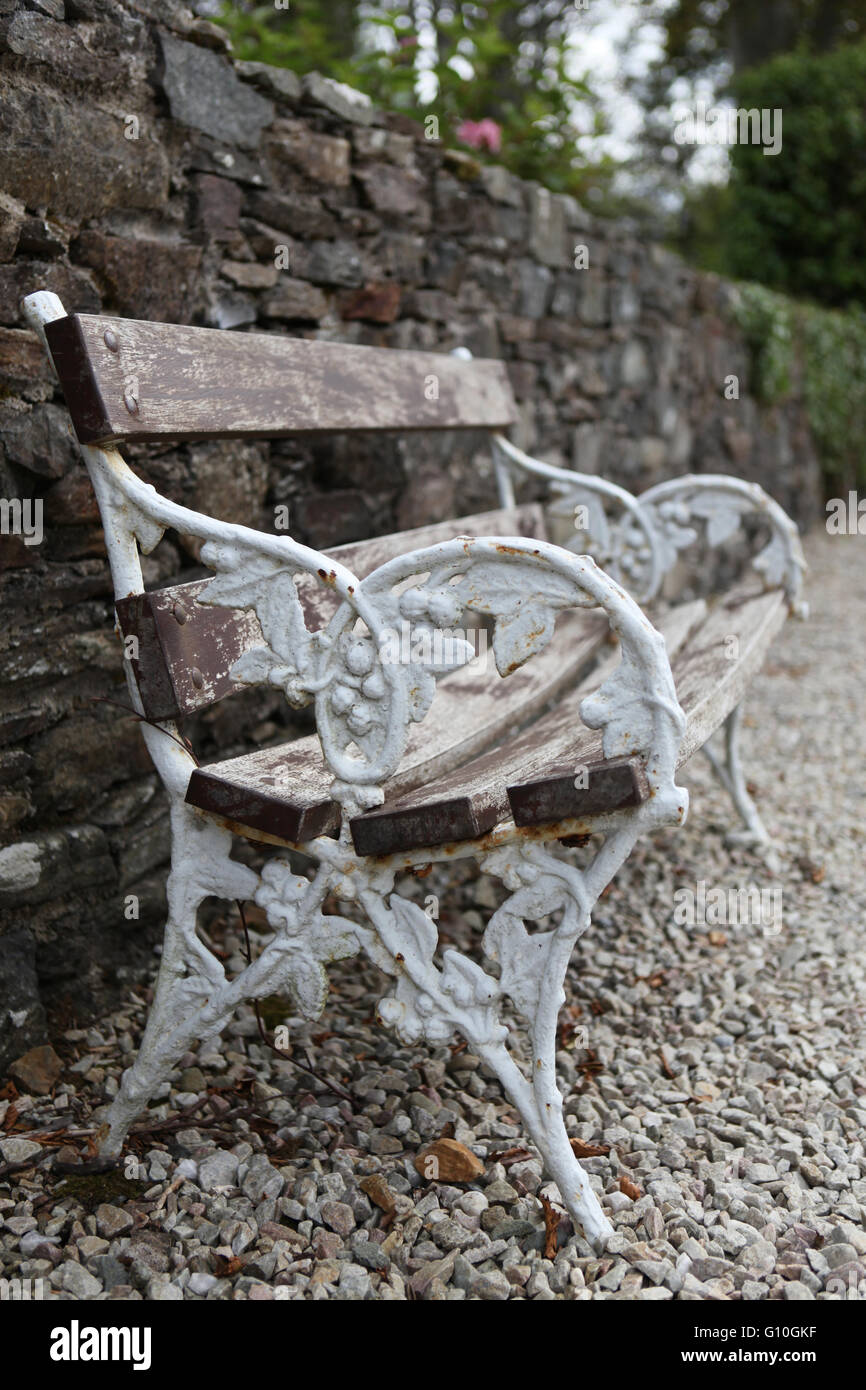 Commemorativa in ferro battuto e panca in legno nel giardino di campagna Foto Stock