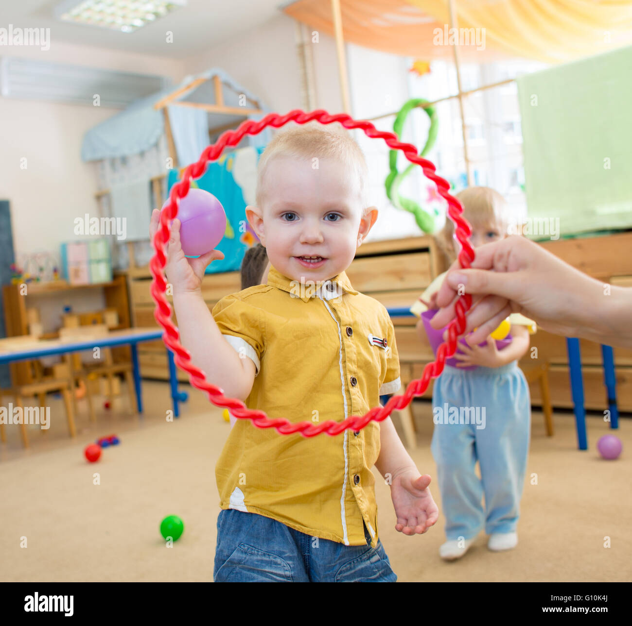 Capretto felice giocando con la palla e anello in kindergarten Foto Stock