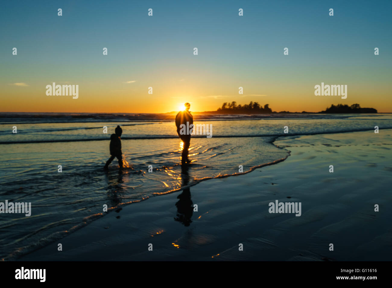 Padre e figlio a piedi nel surf a Chesterman Beach a Tofino, British Columbia Foto Stock