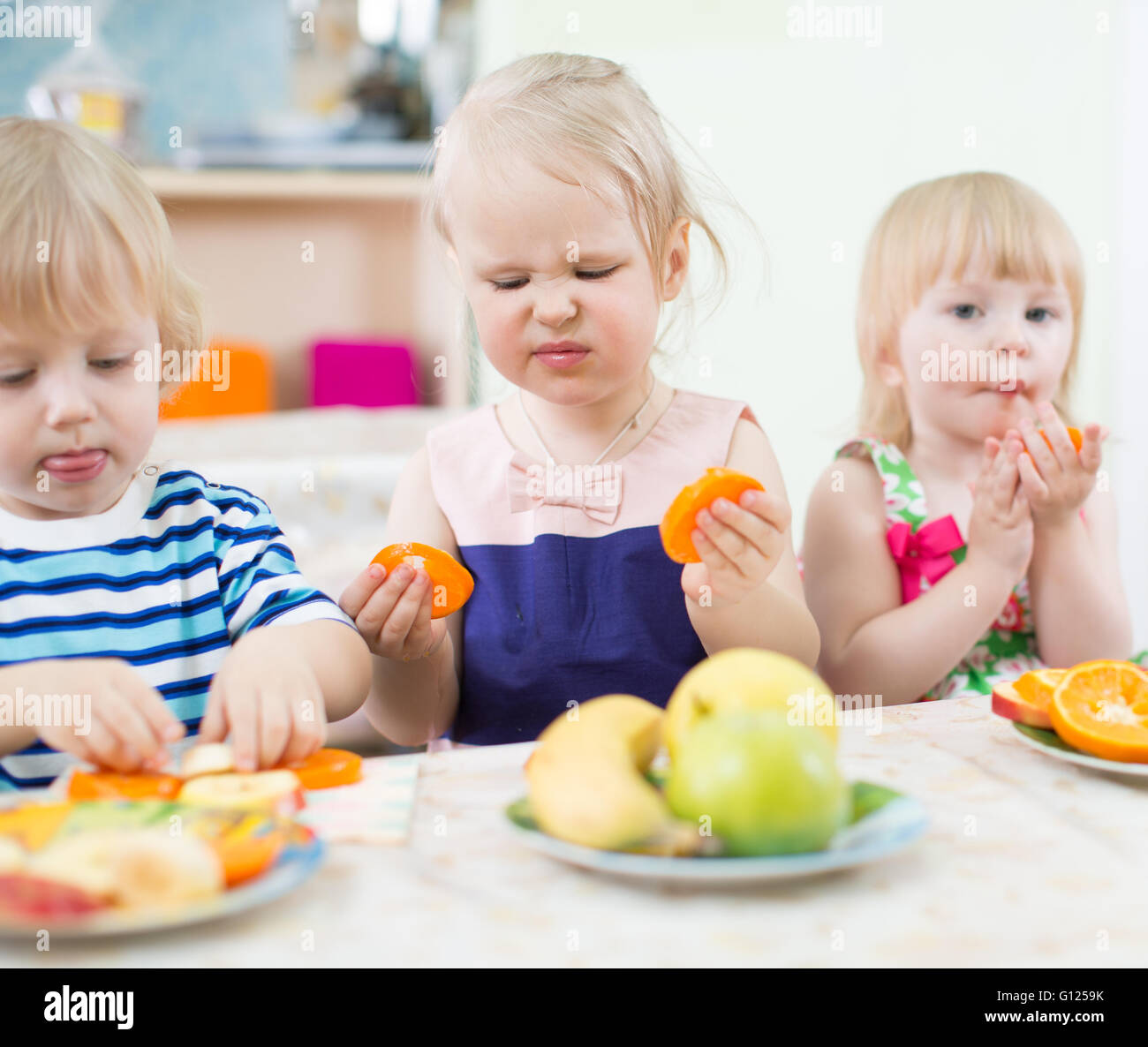 Bambini divertenti mangiare frutta nella scuola materna Foto Stock