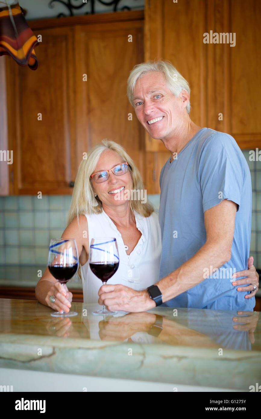 Coppia senior godendo il pensionamento in cucina mentre avente il vino rosso Foto Stock