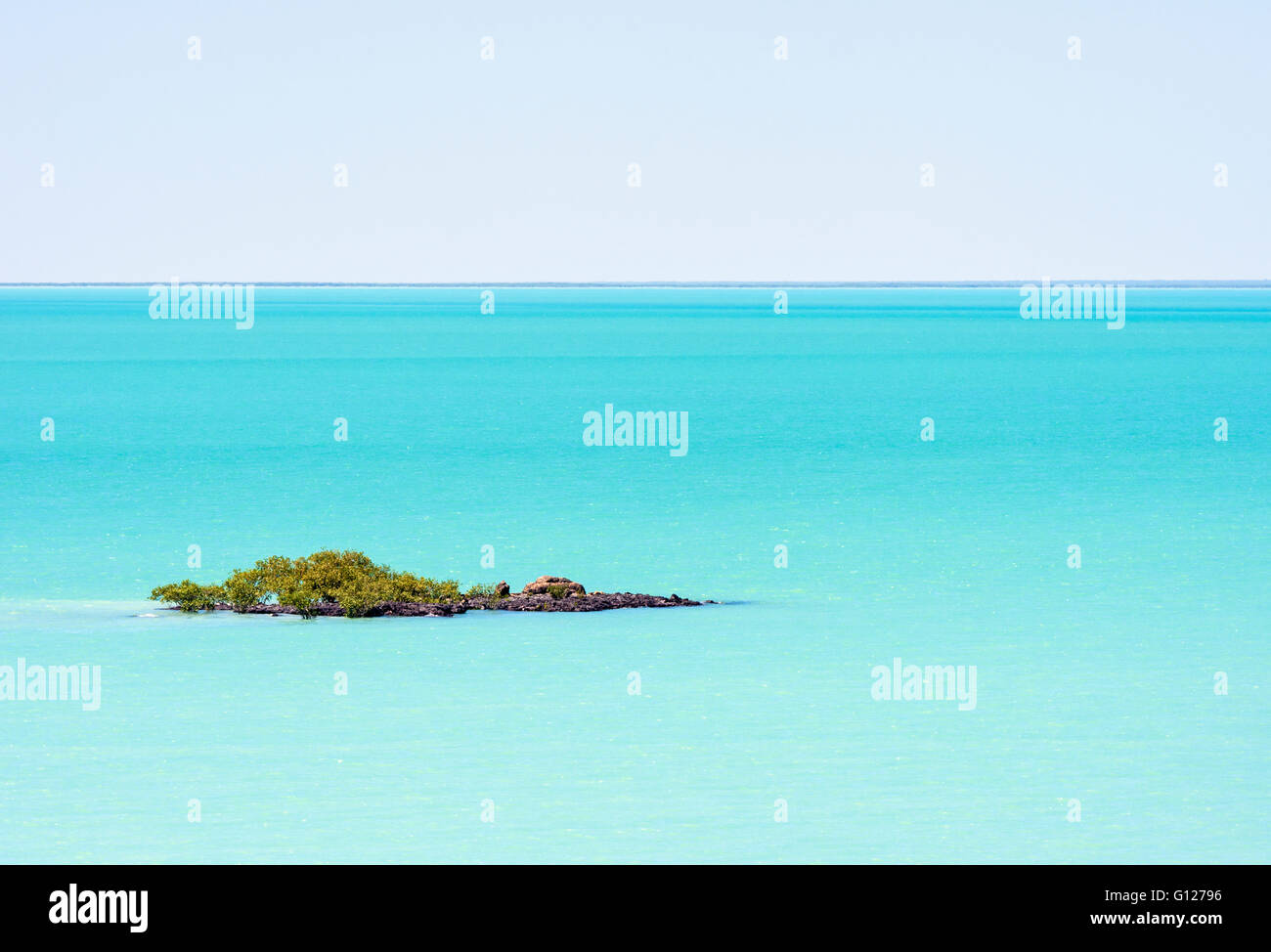 Piccolo promontorio roccioso coperto di mangrovie nelle acque azzurre del mare in Roebuck Bay, Broome, Kimberley, Australia occidentale, Australia Foto Stock