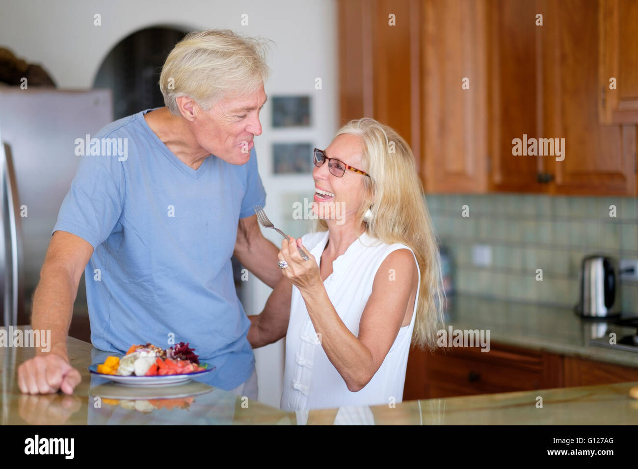 Coppia senior - pensionati moglie alimentazione di pezzi di frutta al marito Foto Stock