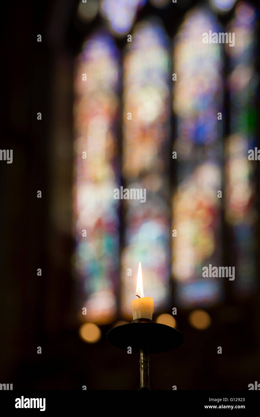 Singola Lit il cero della preghiera di fronte a una moderna vetrata di Ely, selectve focus. Cambridgeshire, Inghilterra Foto Stock