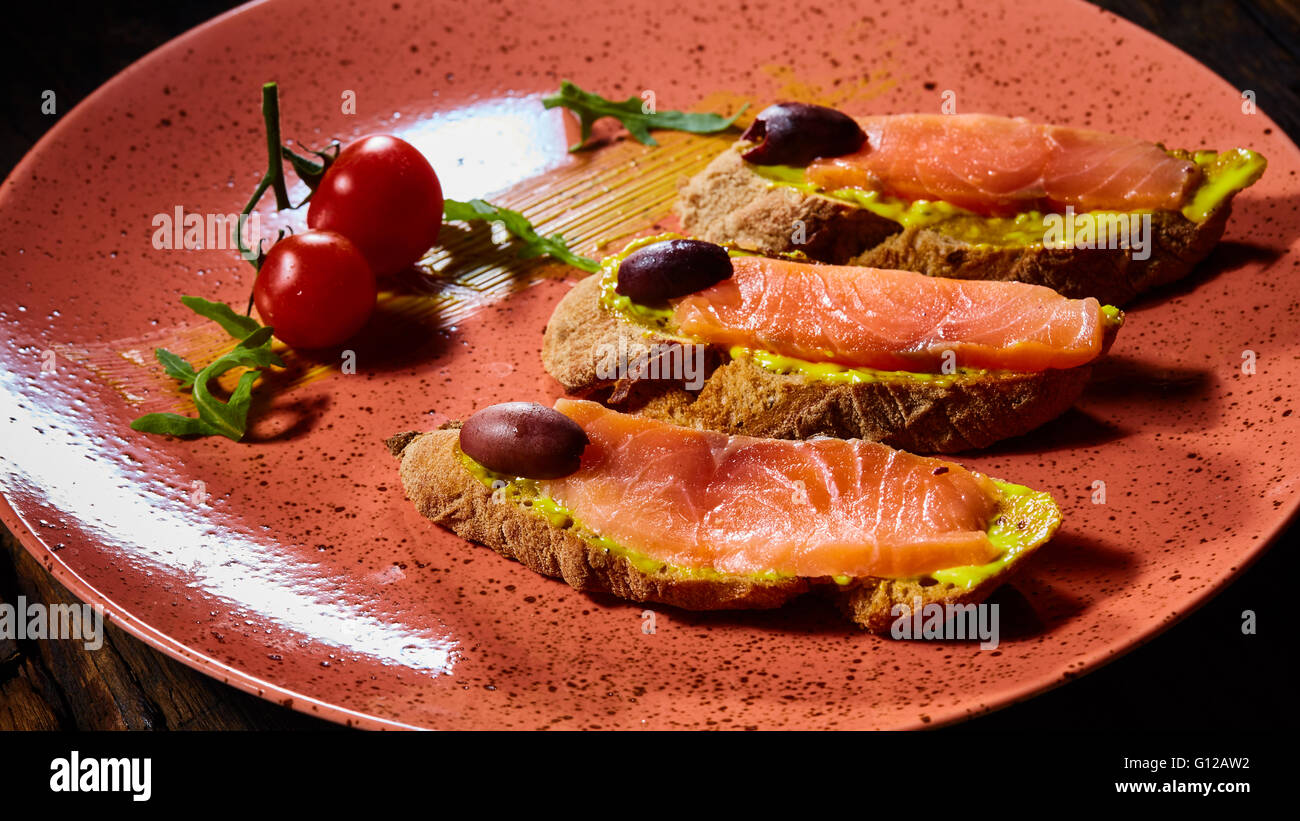 Deliziosa casa salmone affumicato senza glutine crostino guarnito con pomodorini e olive Foto Stock