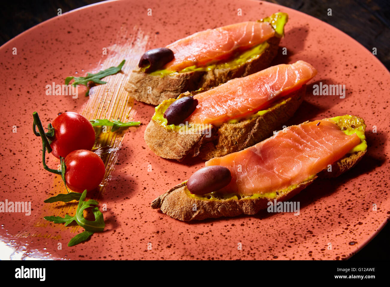 Deliziosa casa salmone affumicato senza glutine crostino guarnito con pomodorini e olive Foto Stock