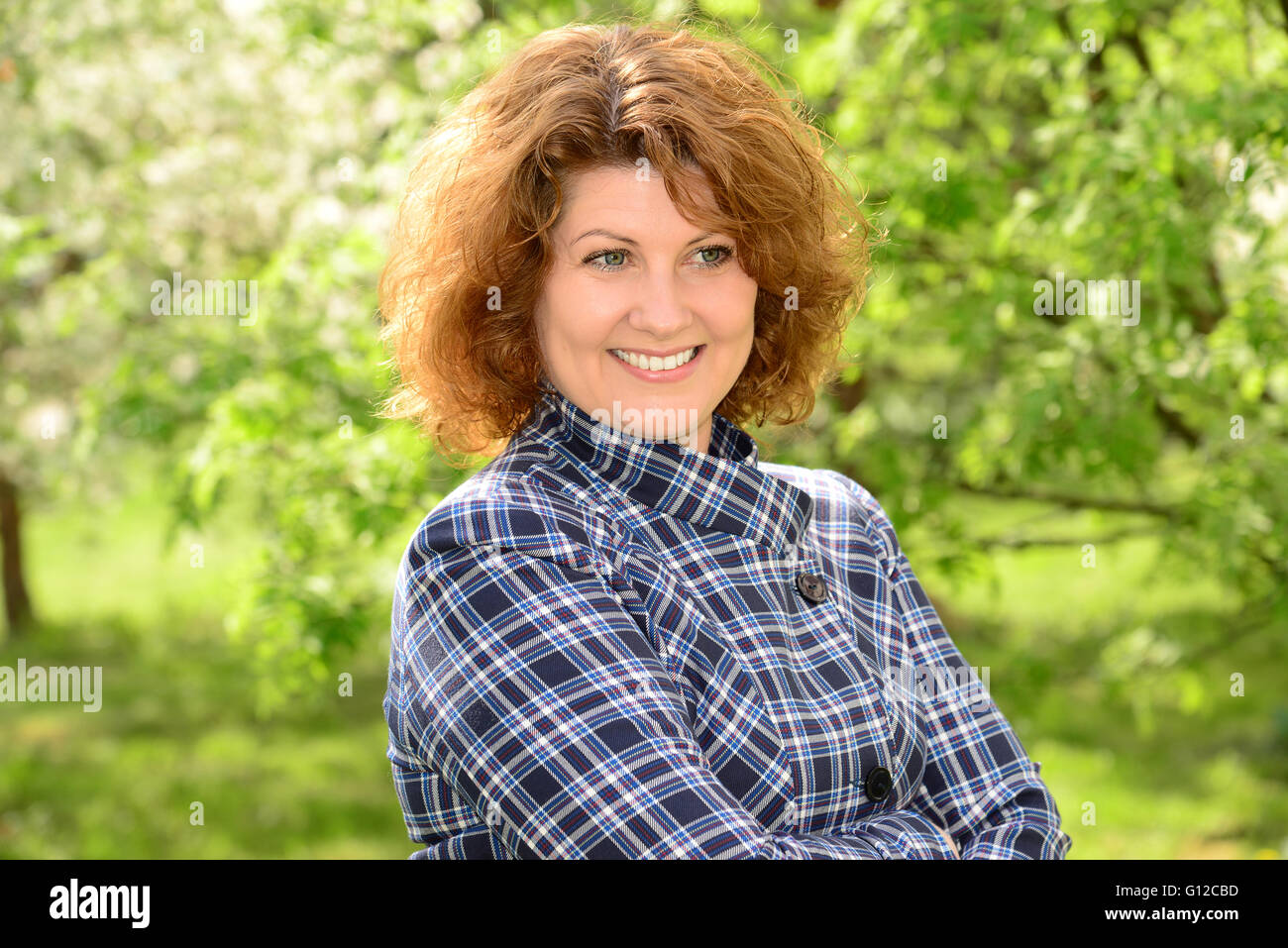 Curly sorridente donna di mezza età al di fuori Foto Stock