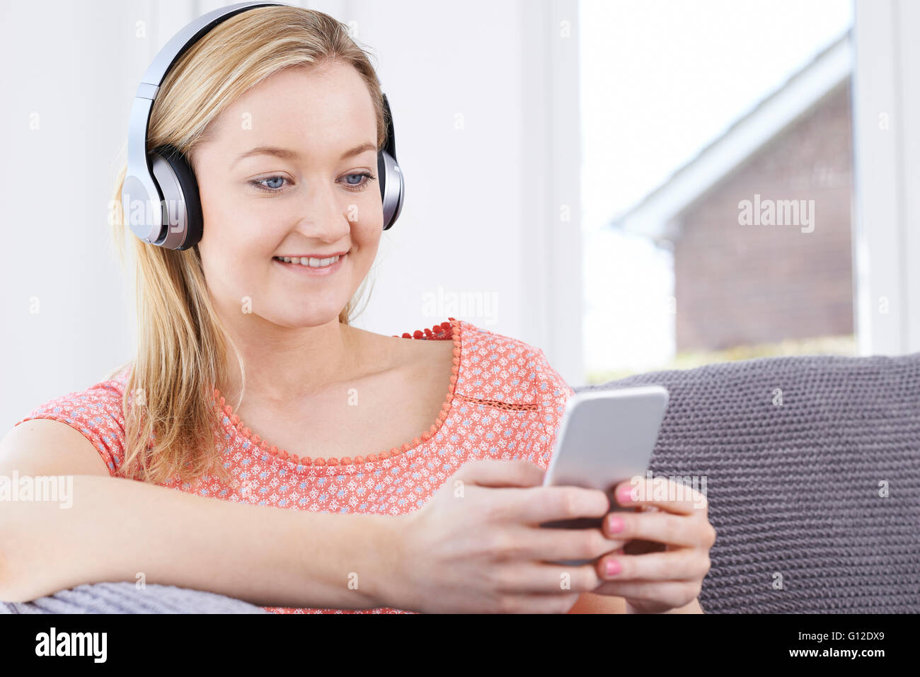Donna streaming di musica dal telefono cellulare alle cuffie senza fili Foto Stock
