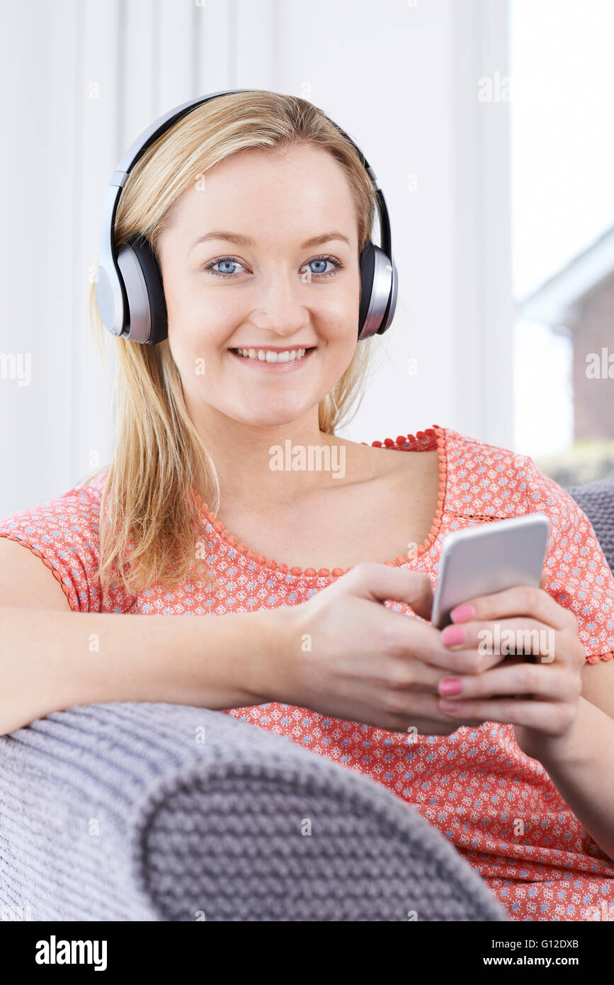 Donna streaming di musica dal telefono cellulare alle cuffie senza fili Foto Stock