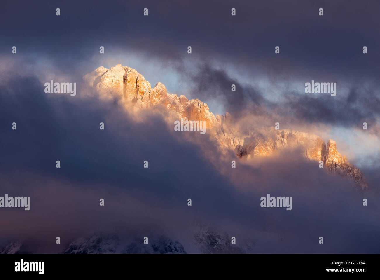 La vetta del Sassolungo al tramonto nella stagione invernale. Cielo nuvoloso. Le Dolomiti Gardena. Alpi Italiane. Europa. Foto Stock