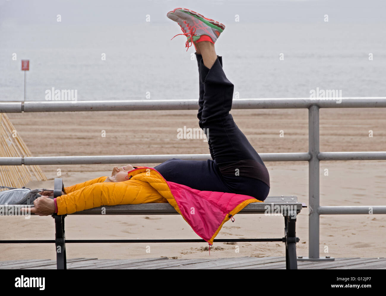 Una donna più anziana non stretching e core Rafforzare esercitazioni sul lungomare di Brighton Beach, Brooklyn, New York Foto Stock