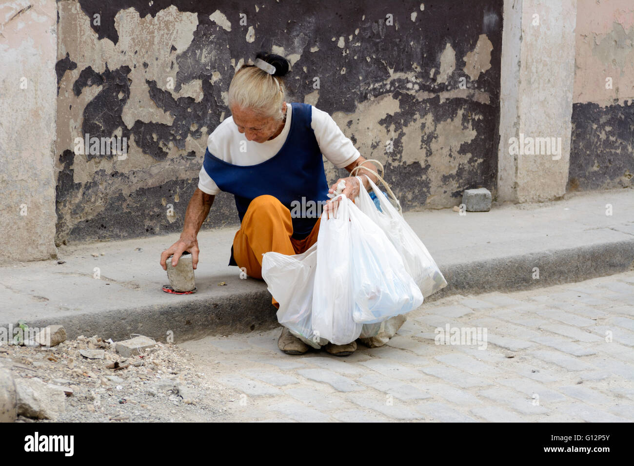 Una donna anziana raccoglie lattine da vendere per riciclaggio da strade di l'Avana Vecchia Havana, Cuba Foto Stock