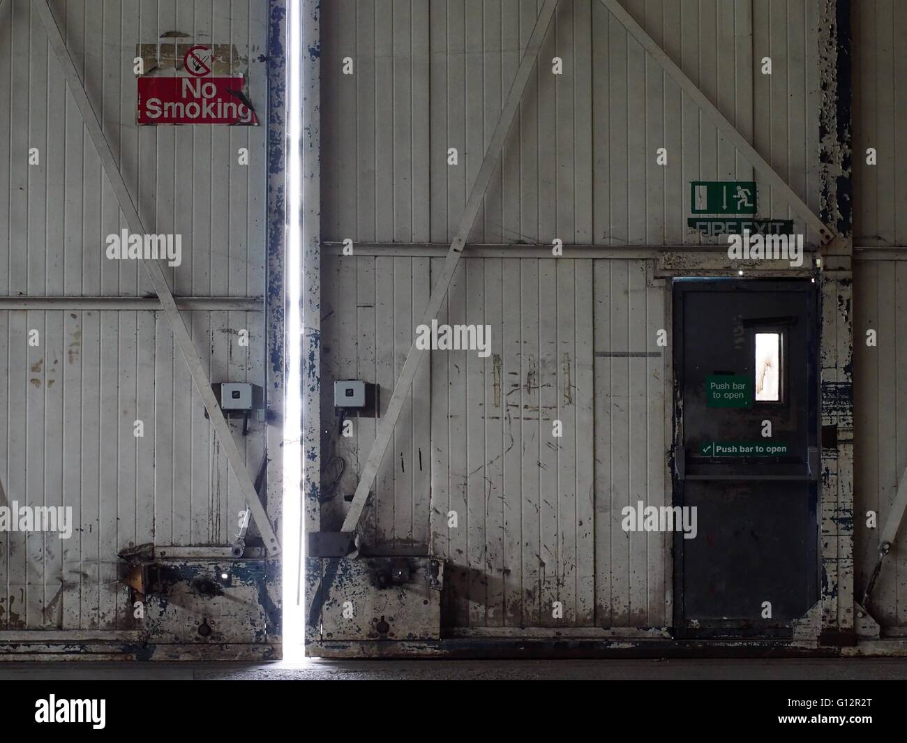 Aeromobile hangar porte con nessun simbolo del fumo e fuoco uscire segno sopra il fuoco alla porta di uscita Foto Stock