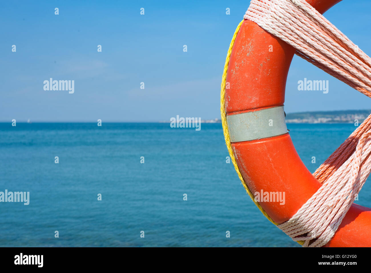 Ciambella rossa simbolo di sicurezza vicino sul vuoto fuori fuoco mare blu in background Foto Stock