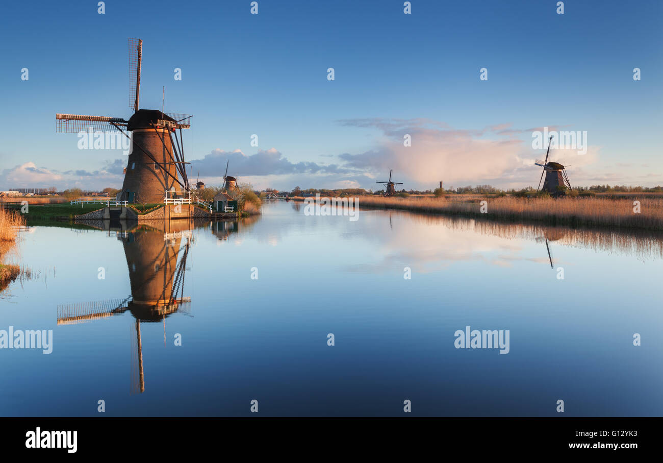 Paesaggio di primavera con bella tradizionali mulini a vento olandese vicino a canali di acqua con la riflessione in acqua a sunrise Foto Stock