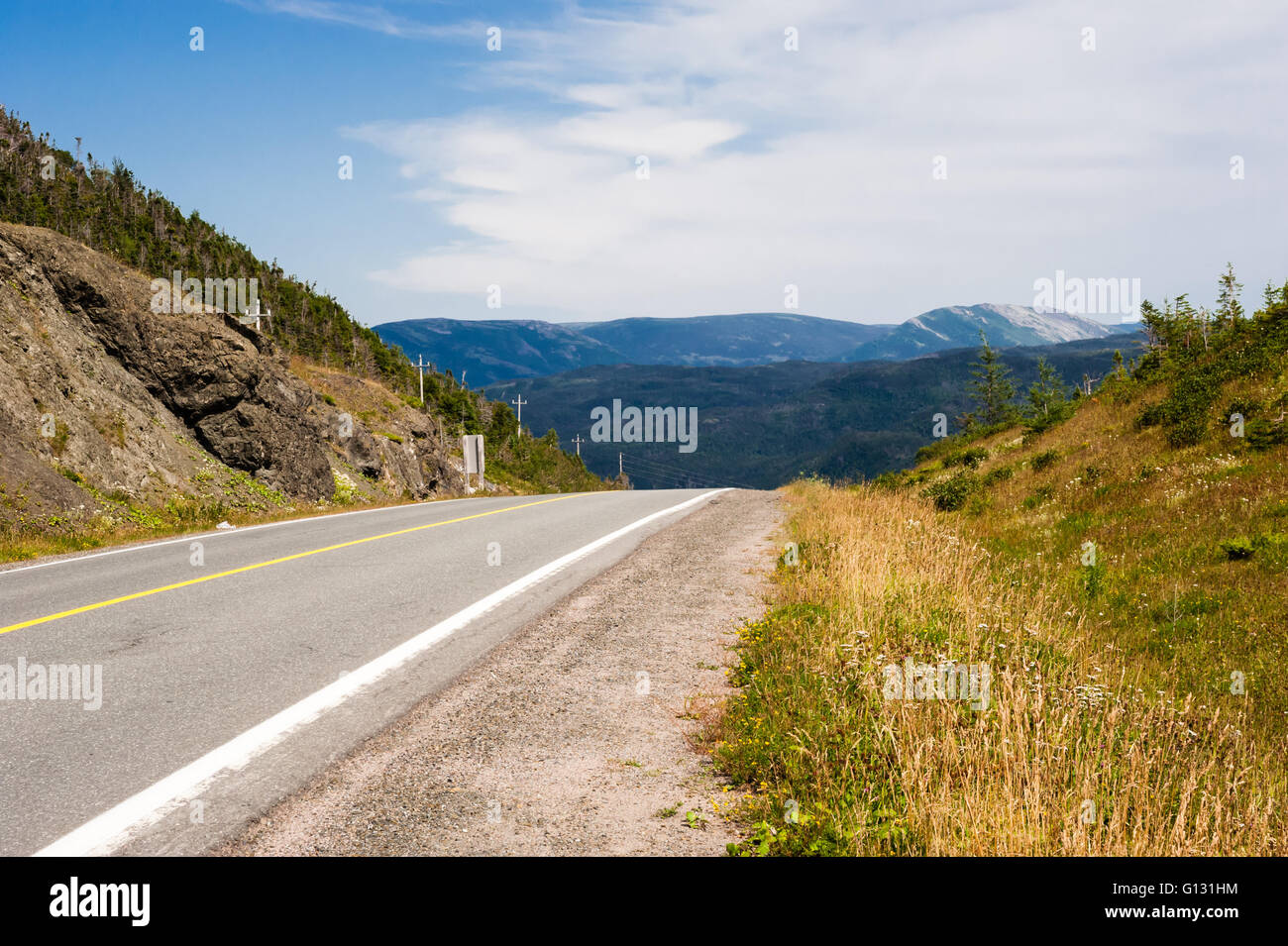 Svuotare lastricata asfalto e ghiaia spallamento contro le colline e le montagne in distanza, nel Parco Nazionale Gros Morne, Terranova. Foto Stock