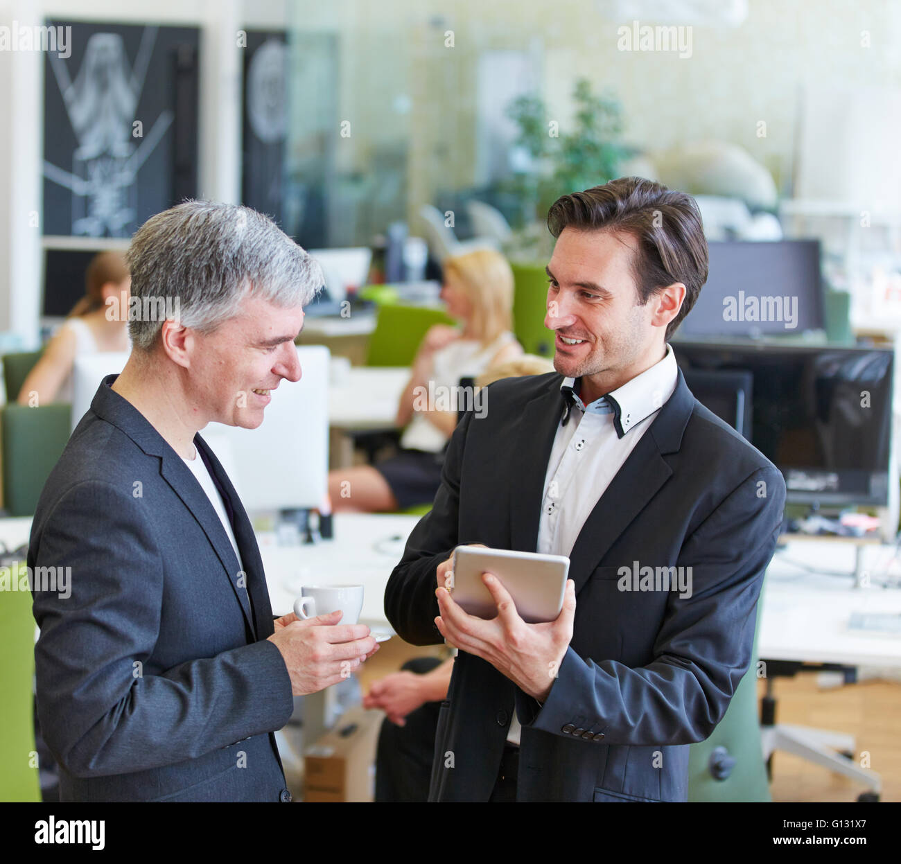 Due persone di affari con computer tablet parlando in ufficio Foto Stock