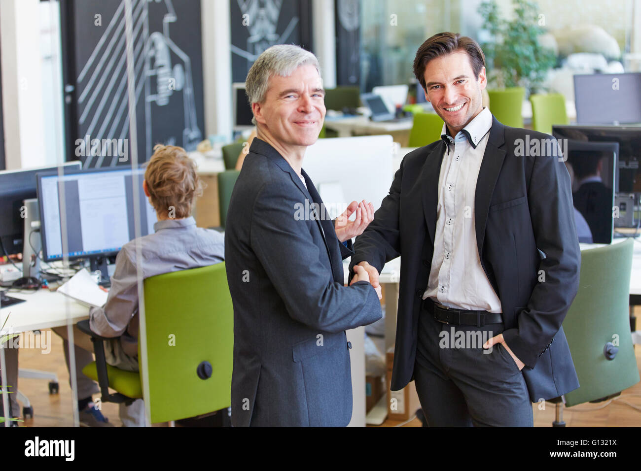 Due sorridente la gente di affari fornendo stretta di mano in ufficio Foto Stock