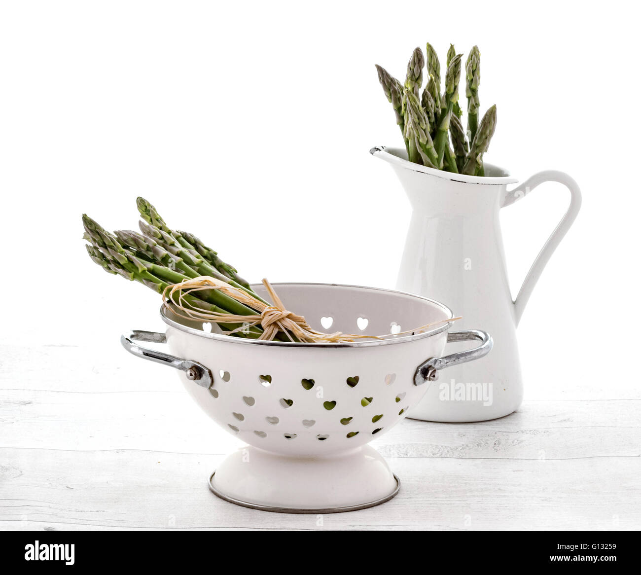 Freschi asparagi verdi in scolapasta e la brocca sulla vecchia sullo sfondo di legno Foto Stock