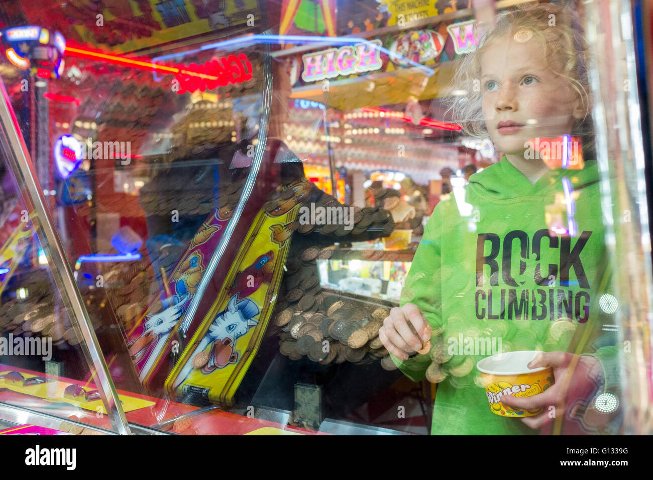 Ragazza giovane riflessa nel vetro di un sala giochi sul lungomare di Morecambe, Regno Unito Foto Stock
