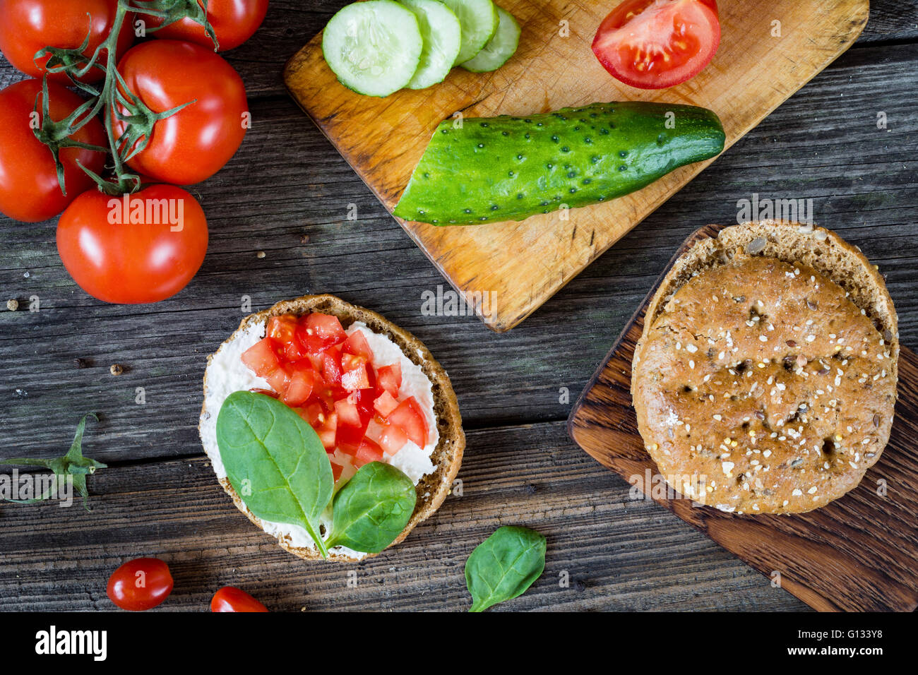 Snack sani: pane piatto, crema di formaggio, pomodori e baby spinaci. Tabella vista dall'alto il cibo, laici piatta Foto Stock