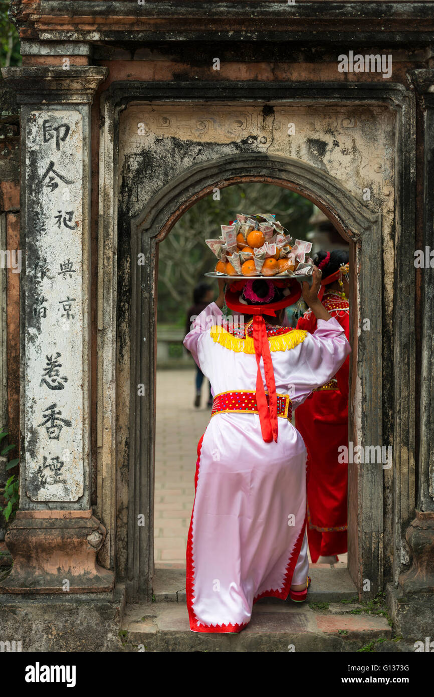 Donna in abito tradizionale che porta un vassoio per una cerimonia durante la Truong Yen Festival di Hoa Lu templi in Nihn Bihn, Vietnam Foto Stock