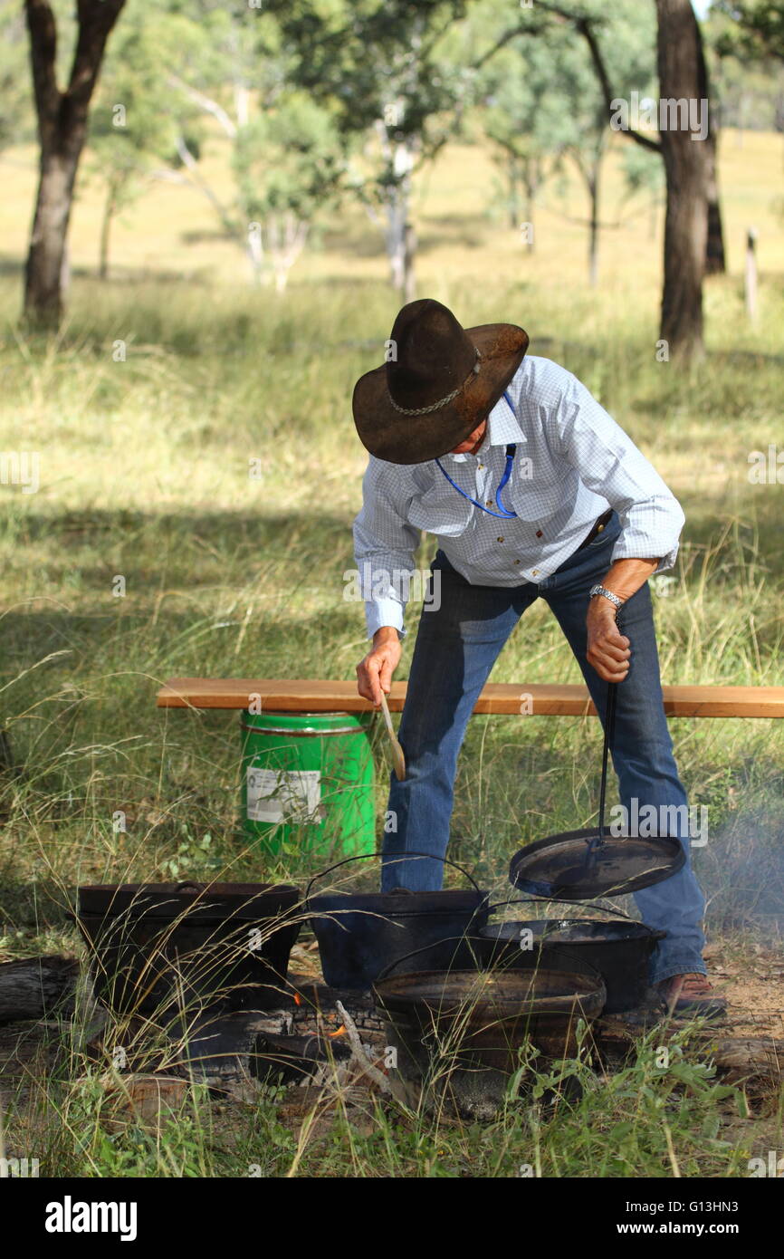 Un paese più maturo lady cottura con forni di camp o olandese forni, in un campo di fuoco per la carità Eidsvold Cattle Drive in QLD. Foto Stock