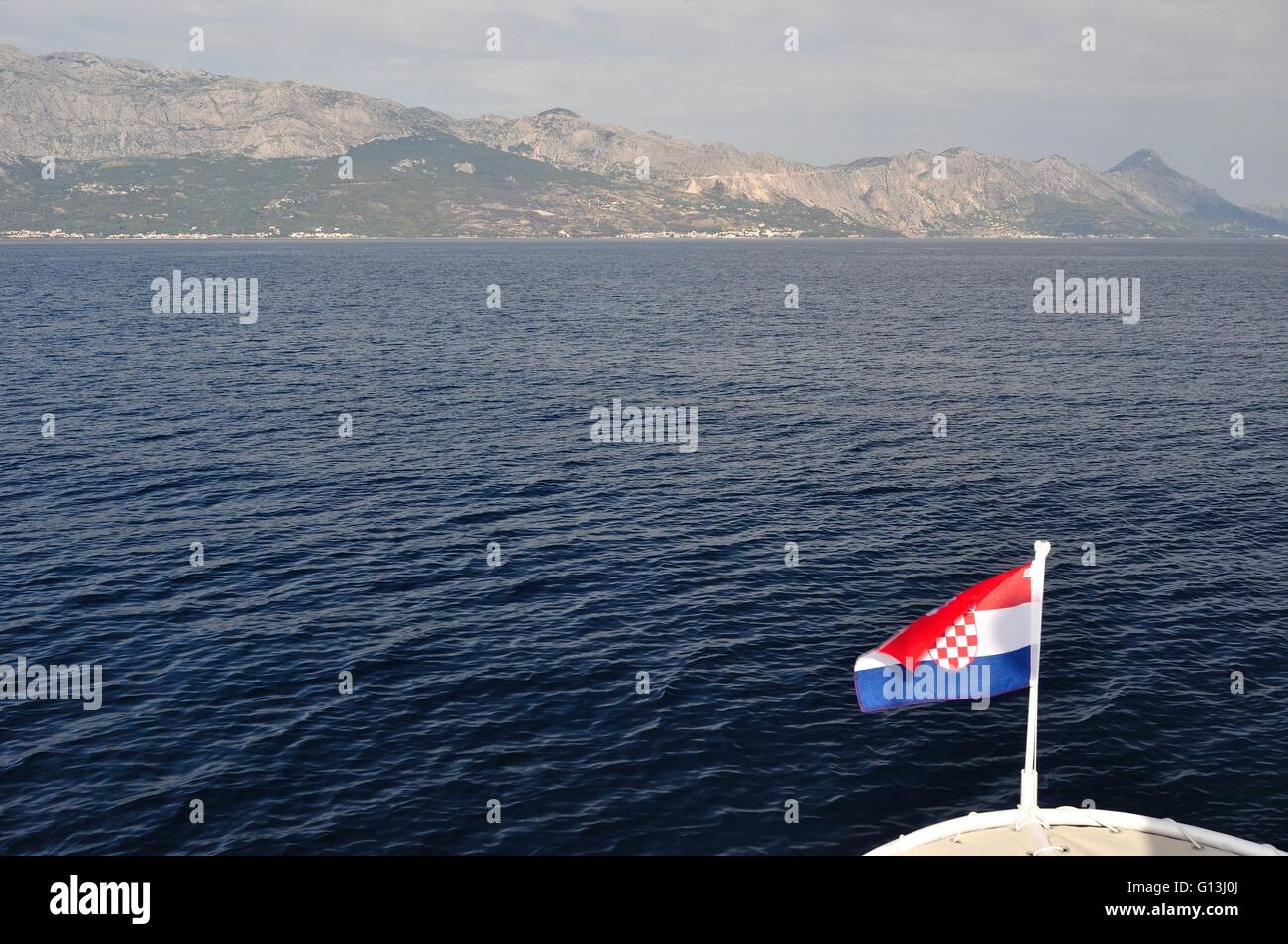 Mare Adriatico in Croazia con il monte Biokovo in background. Vista dalla nave. La bandiera croata in basso a destra dell'immagine Foto Stock