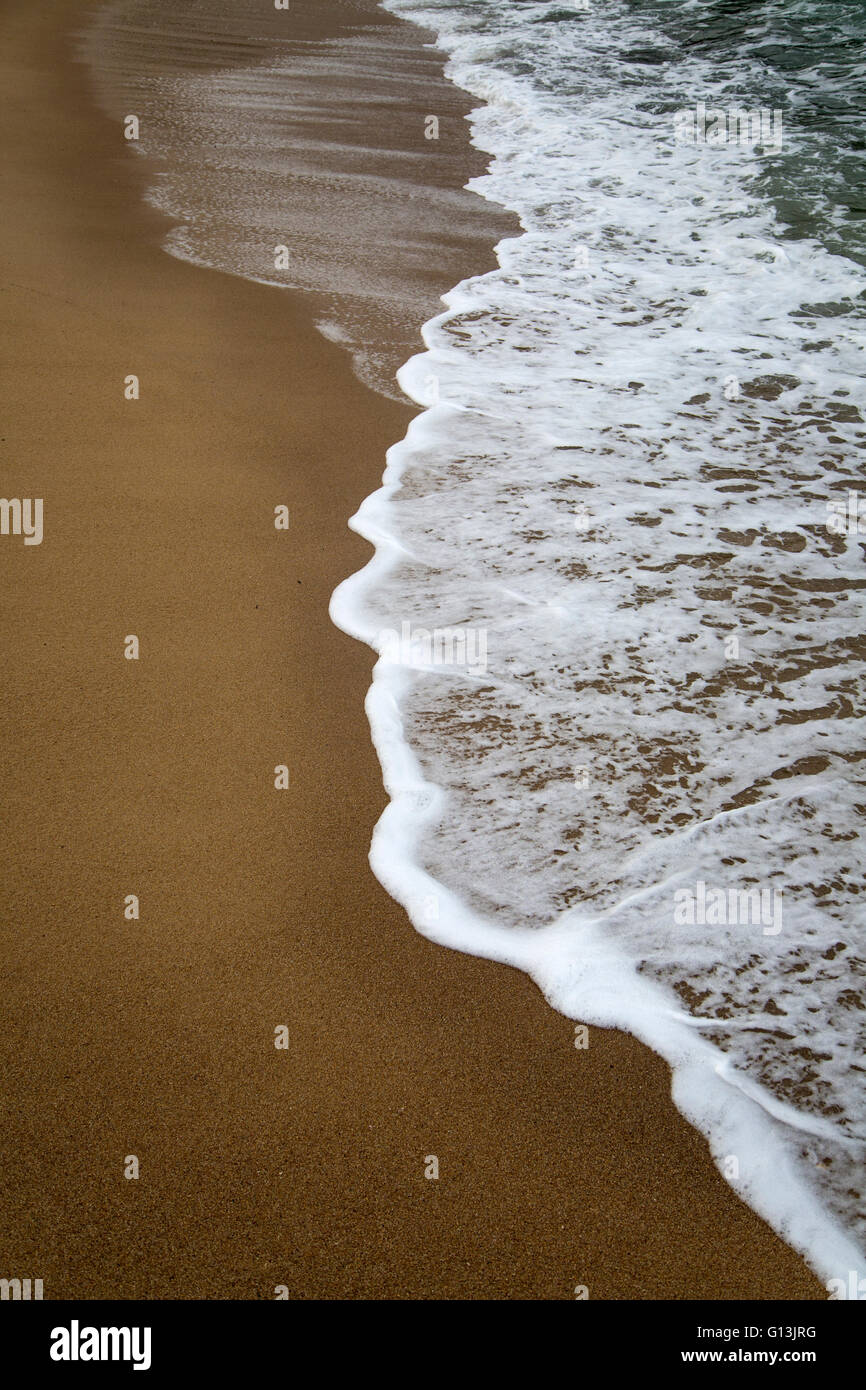 Splash di onda su una spiaggia di sabbia Foto Stock