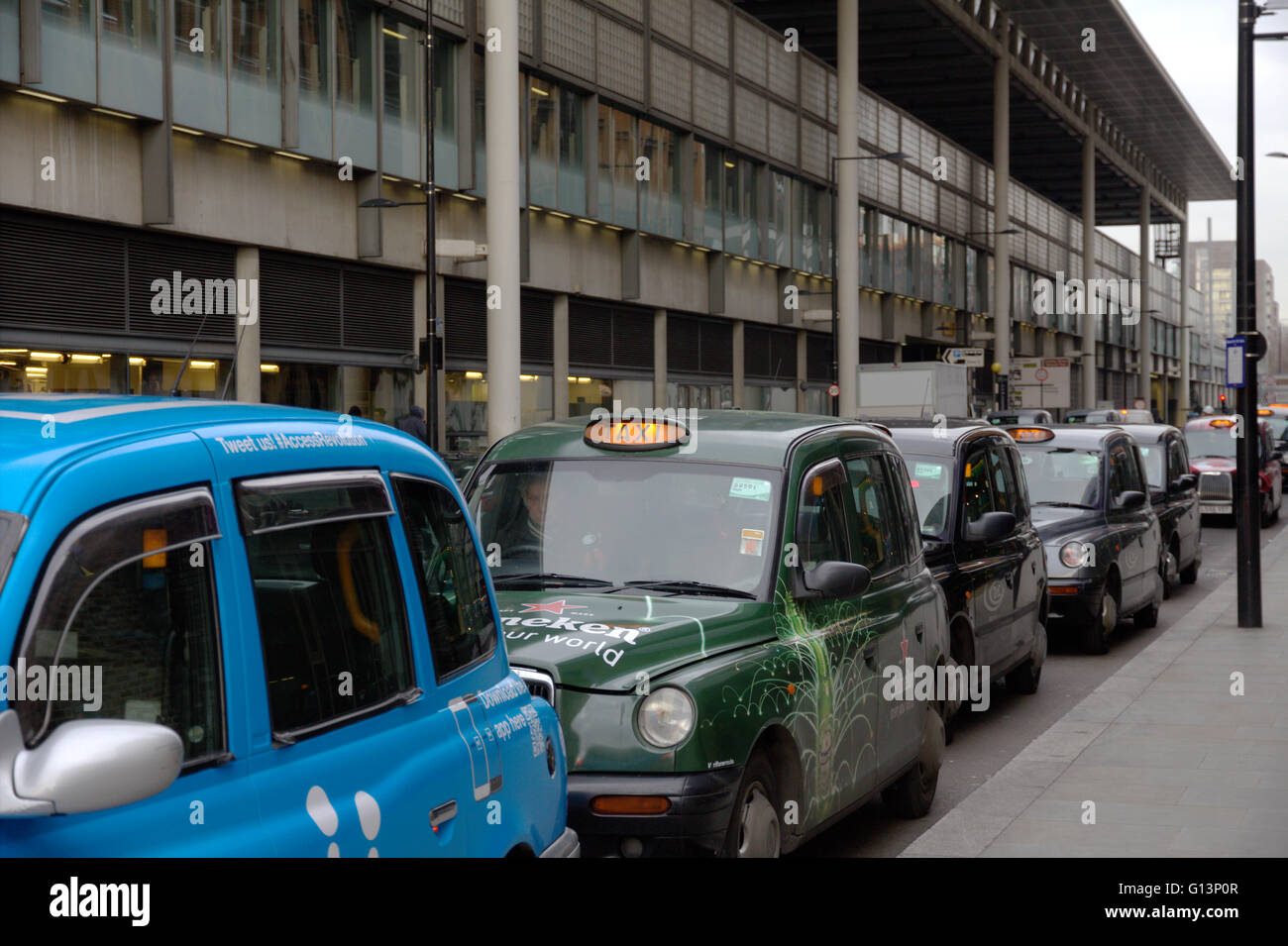 Una coda di London Black Cab taxi in fila in corrispondenza di una stazione di taxi in attesa di raccogliere passeggeri vicino a Kings Cross Station con per noleggio illuminato di luce Foto Stock