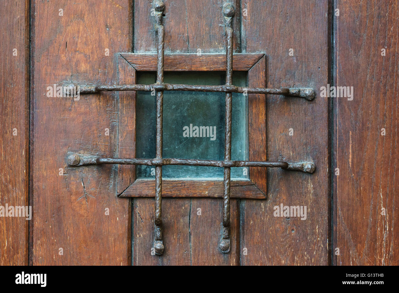 Piccola finestra quadrata con griglia in stile vecchia porta di legno, concetto di confinamento Foto Stock