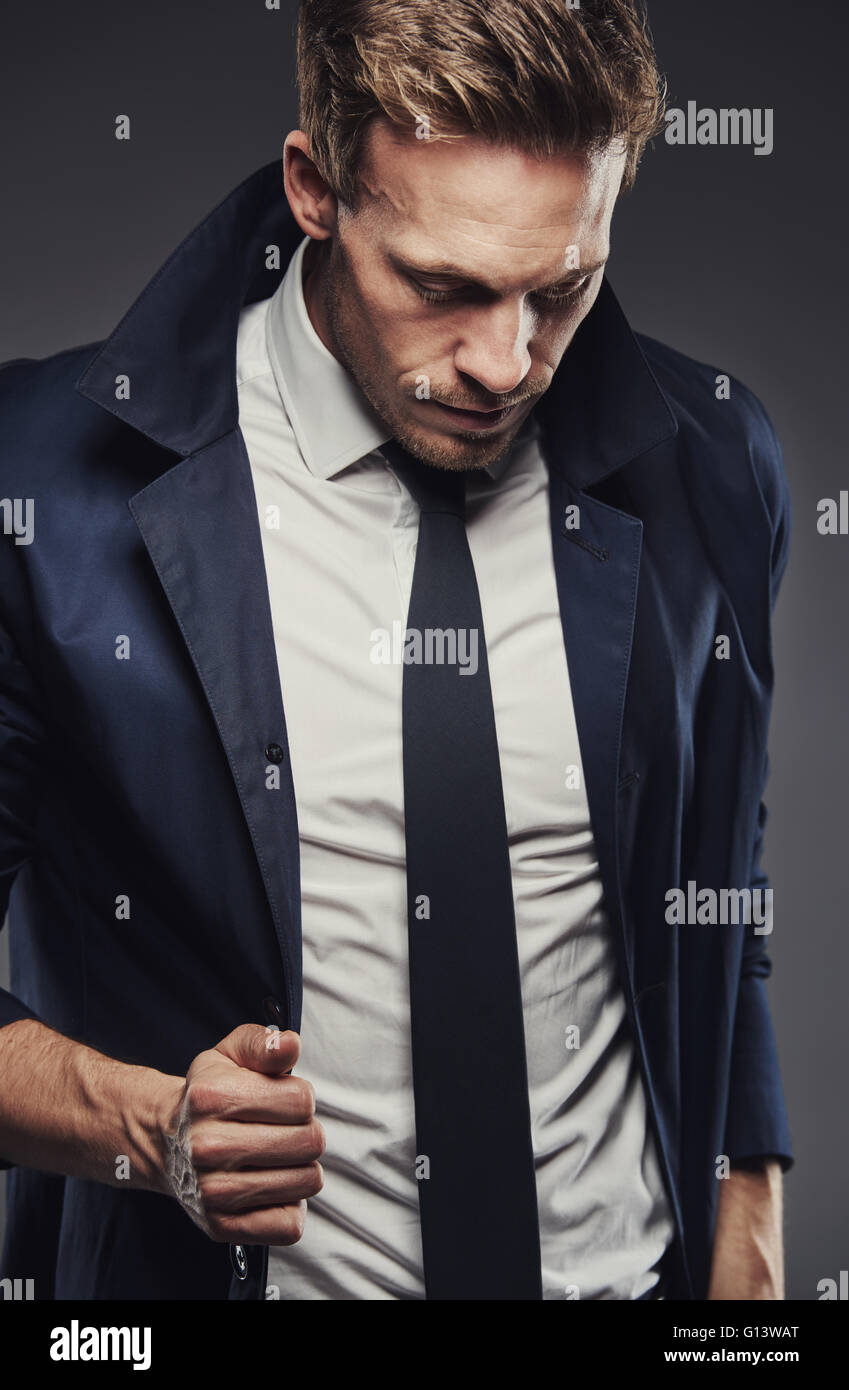 Snappy vestito uomo d affari che indossa cravatta sottile e con il collare rivolto verso l'alto contro uno sfondo scuro Foto Stock