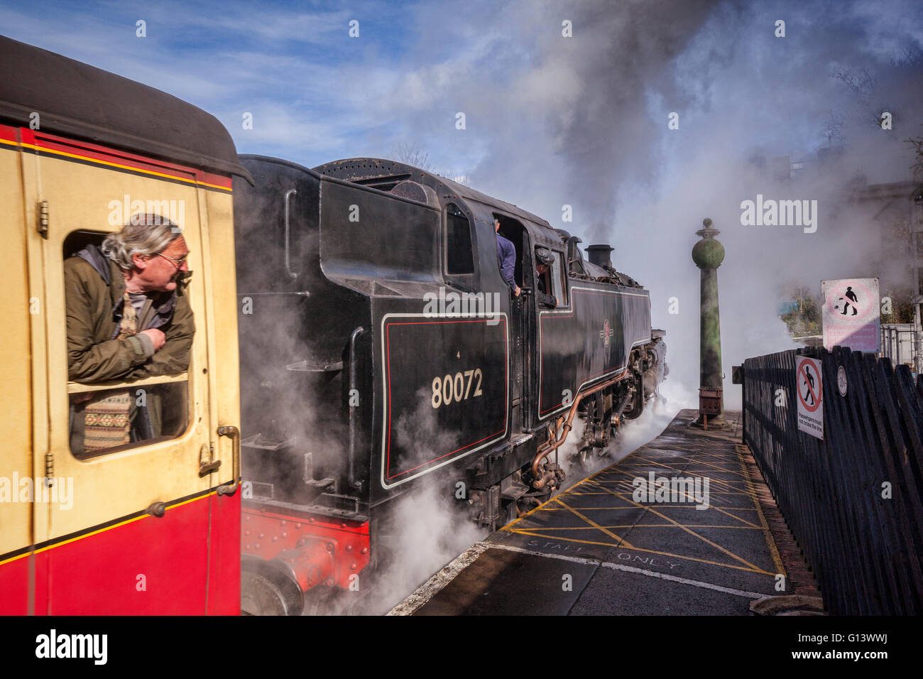 Uomo che guarda fuori della finestra carrello come treno a vapore che lascia la stazione di Pickering, North Yorkshire Moors Railway, Inghilterra, Regno Unito. La messa a fuoco è Foto Stock